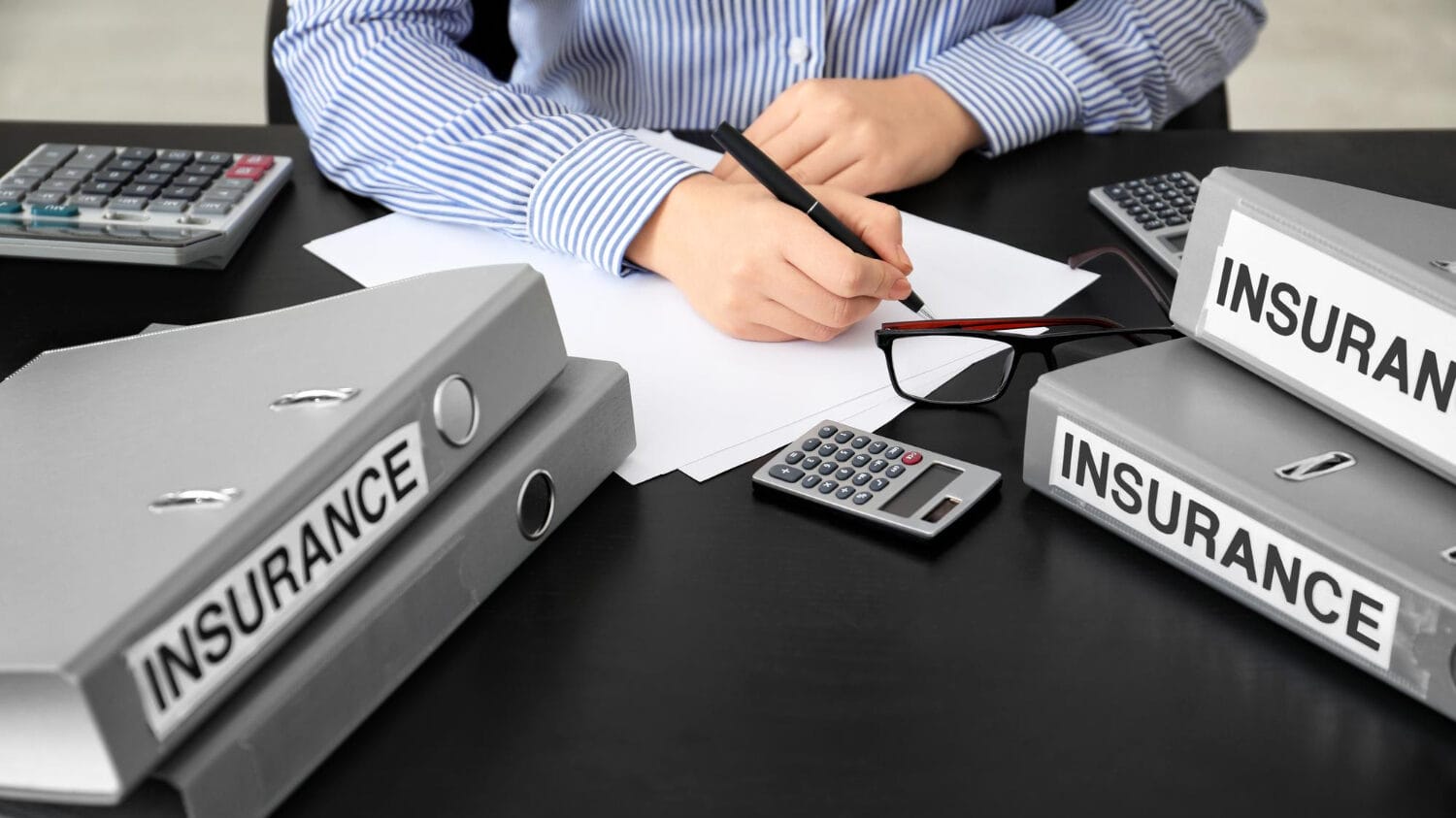 General vs professional liability insurance paperwork and policy files on office desk