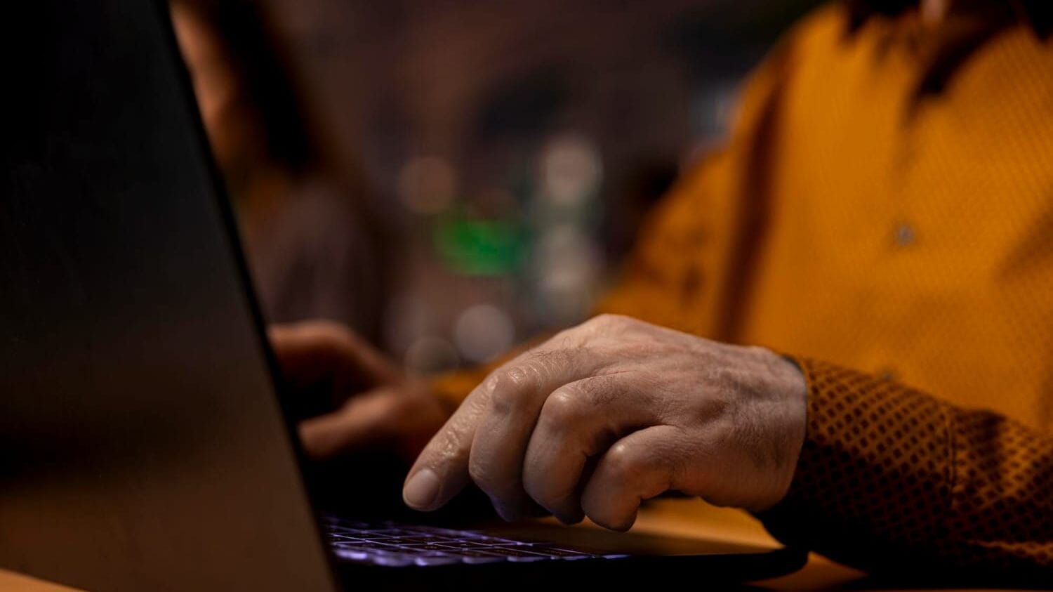 Person typing on laptop at night